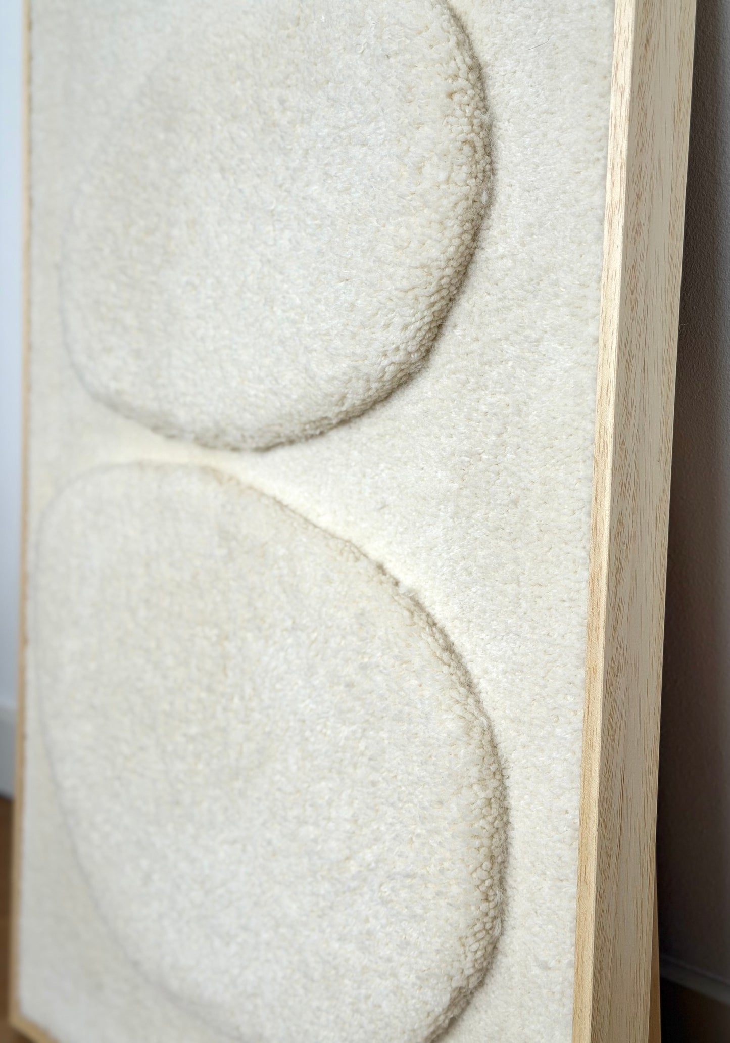 Ecru wool and alpaca tufted wall hanging with two raised pebble shapes