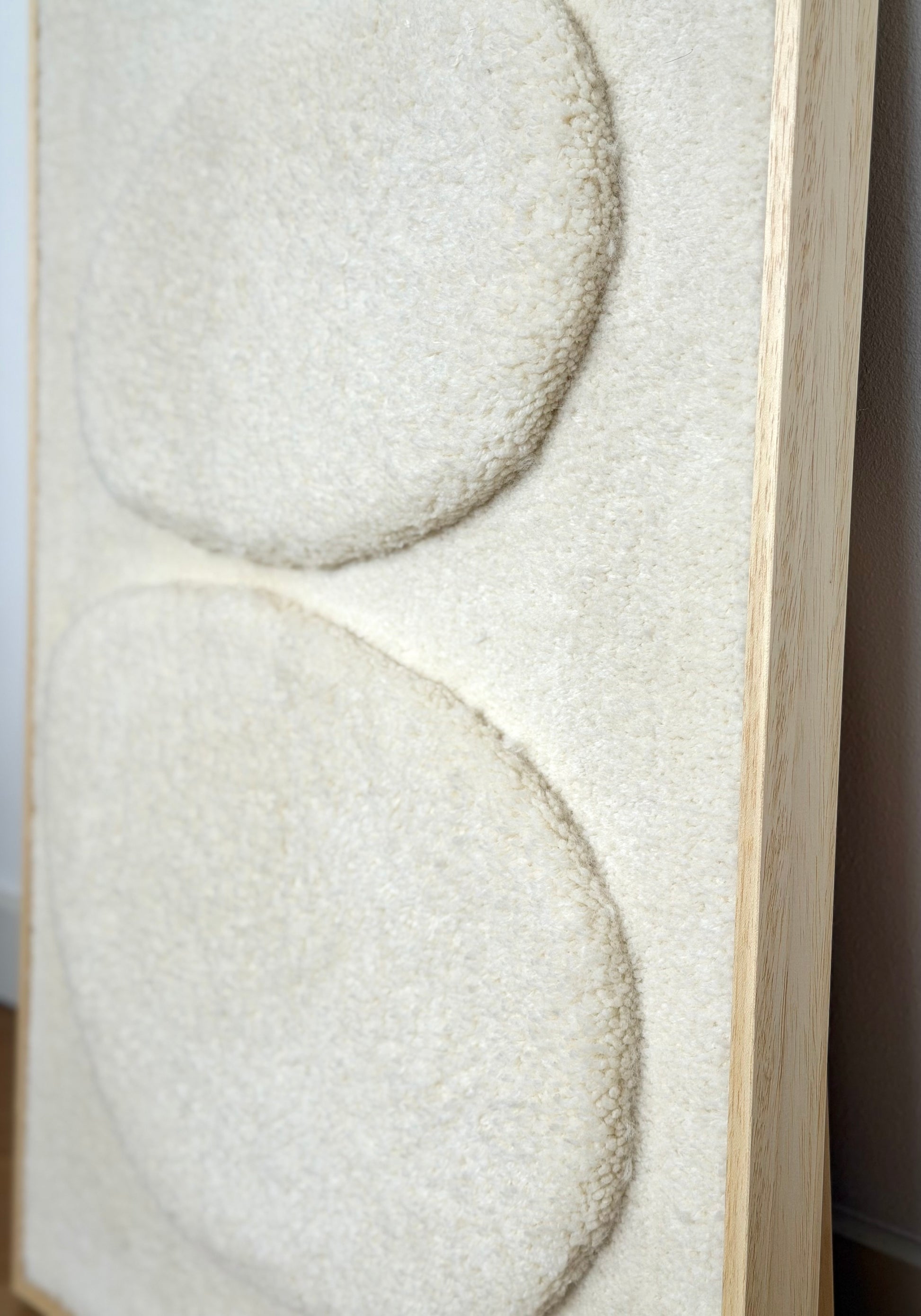 Ecru wool and alpaca tufted wall hanging with two raised pebble shapes