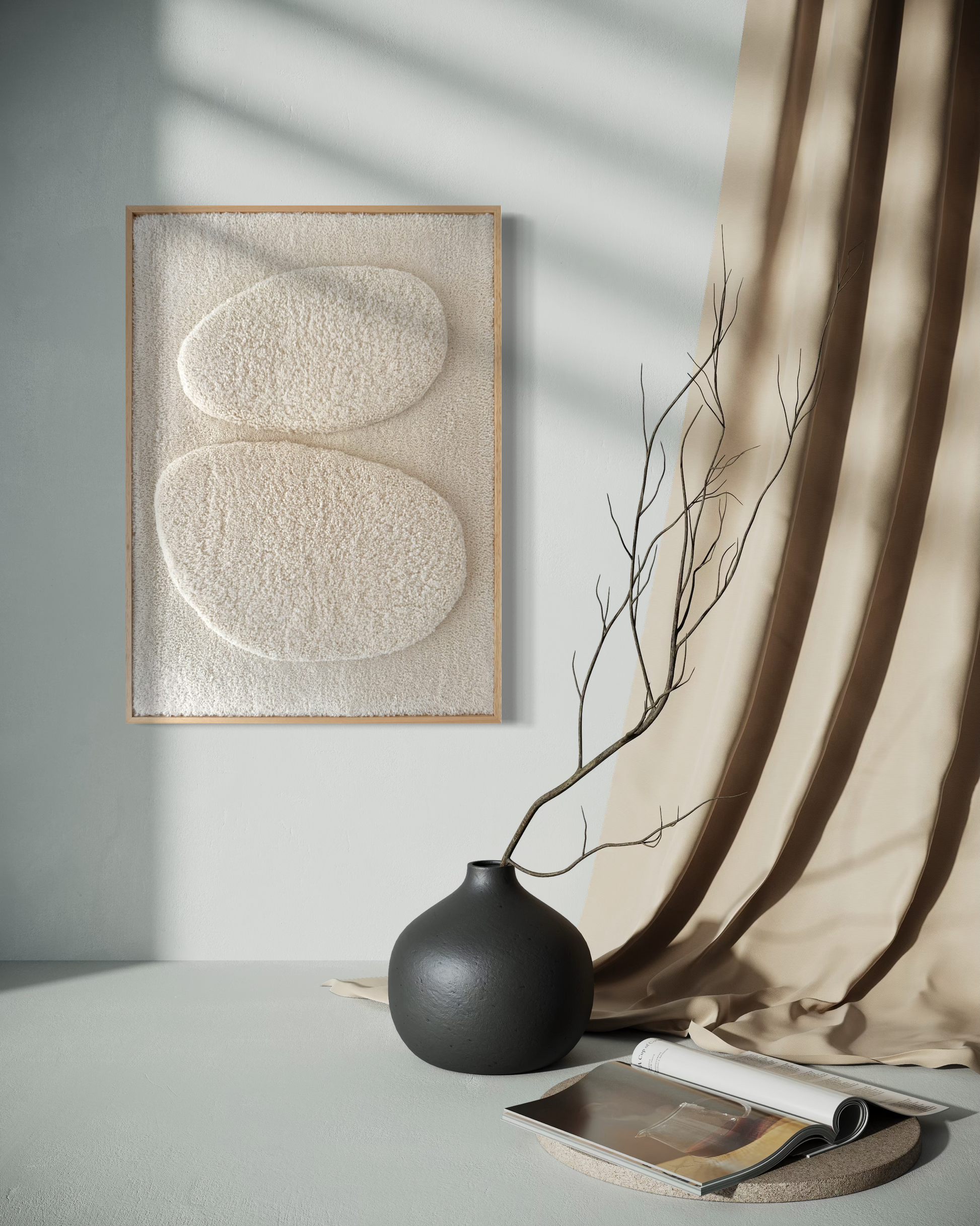 Framed abstract art piece on a wall with a black vase and open book on a surface below.
