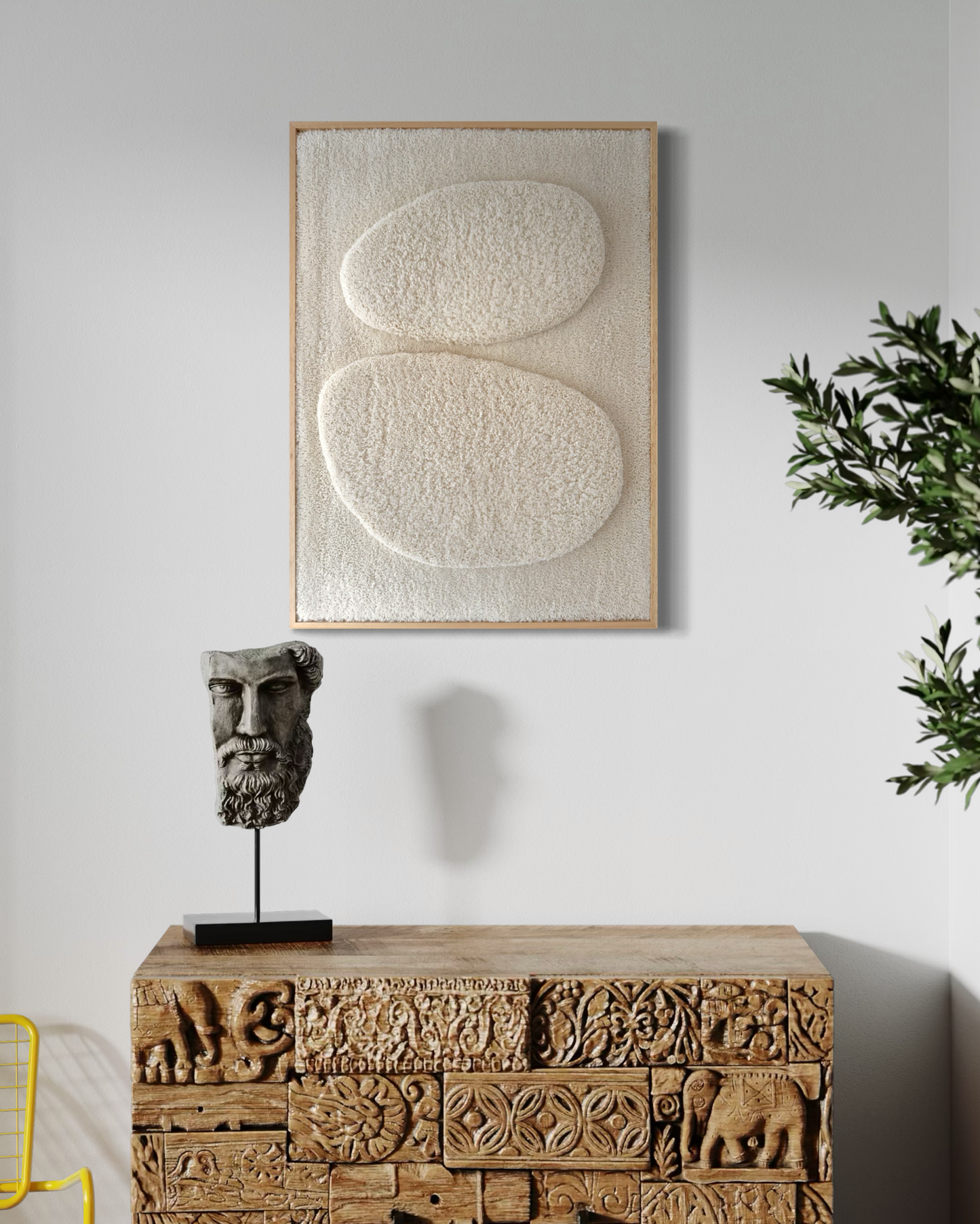 Decorative wall art with abstract design on a white wall above a wooden cabinet with a sculpture.