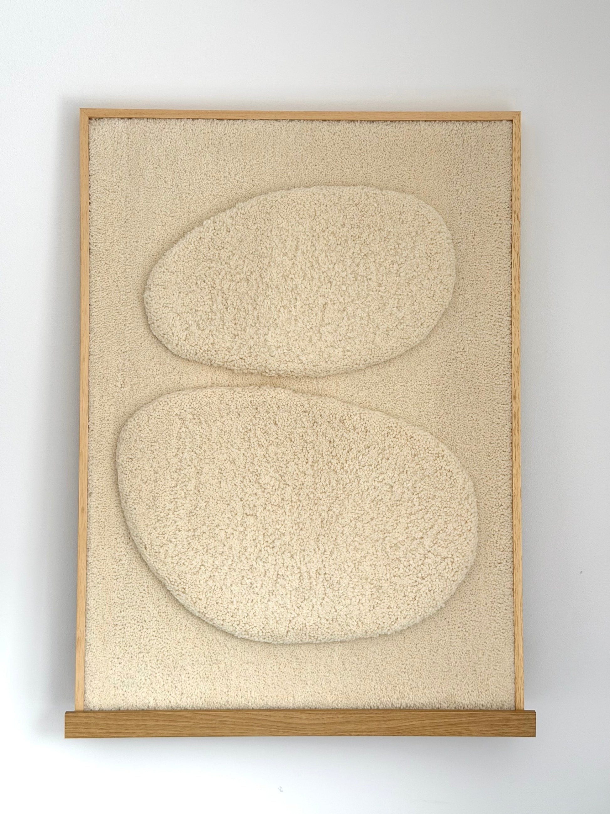 Framed abstract art with two rounded shapes on a textured beige background